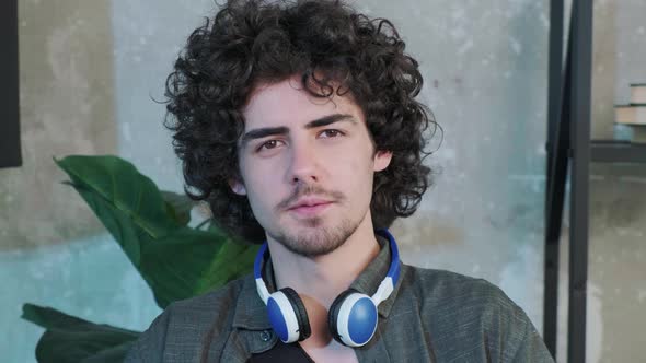 Handsome Young Curly Haired Guy Looking at the Camera and Trying to Explain Something alt