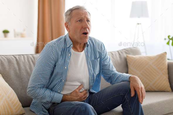 Senior man suffering from stomachache, touching tummy