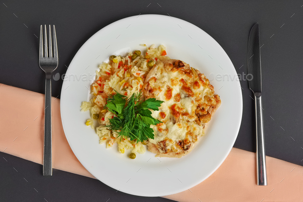 Top view of chicken fillet with mushrooms and cheese garnished with rice, corn and peas