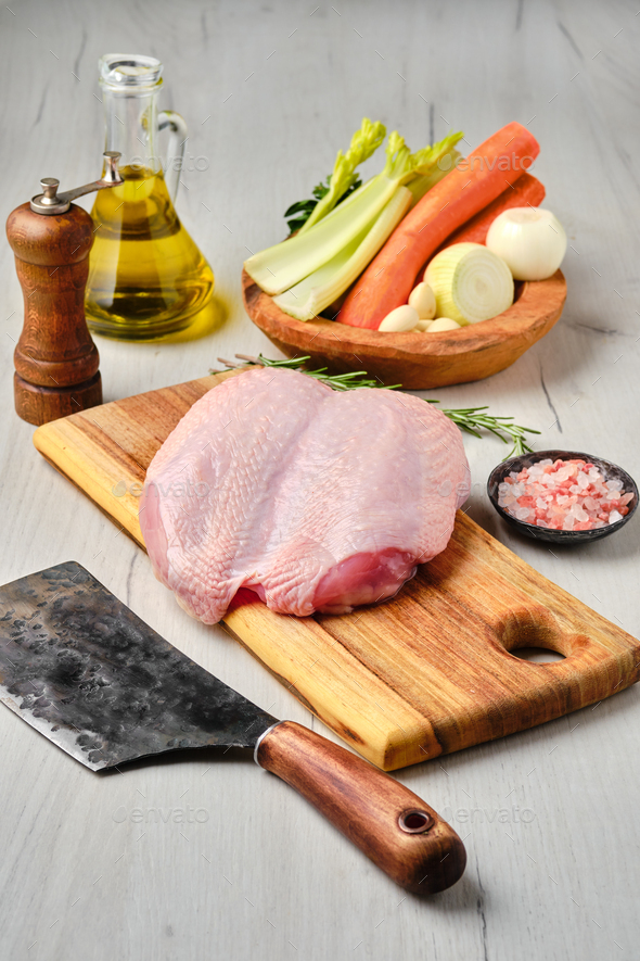 Raw whole chicken breast with skin on carcas with ingredients for