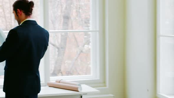 Businessman looking at blueprint alt