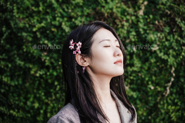 portrait of beautiful chinese asian woman with eyes closed and almond tree flowers.Spring time,relax