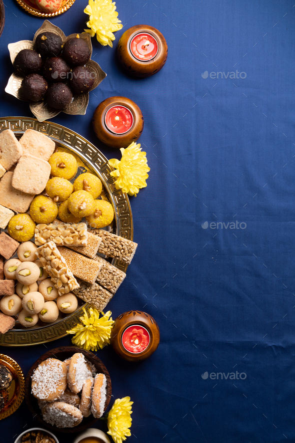 traditional indian sweets on blue background with candles and flowers flat  lay Stock Photo by ilonadesperada