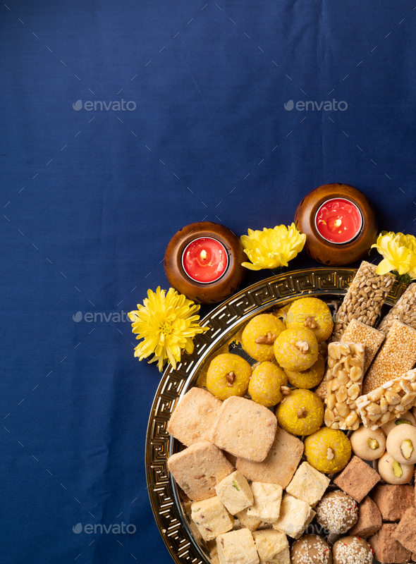 traditional indian sweets on blue background with candles and flowers flat  lay Stock Photo by ilonadesperada