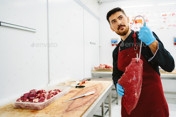 Butcher man holding meat on hook to cut and sell it