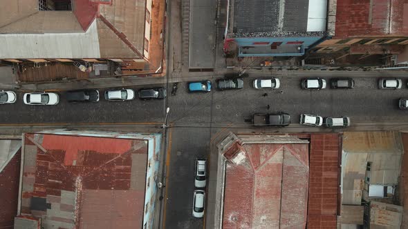 Aerial top down of cars parked inline in narrow street and houses with red rooftops in Valparaiso ci alt