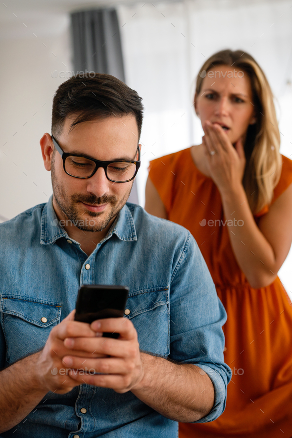 Young couple with smartphone having quarell and marriage conflict because of cheating