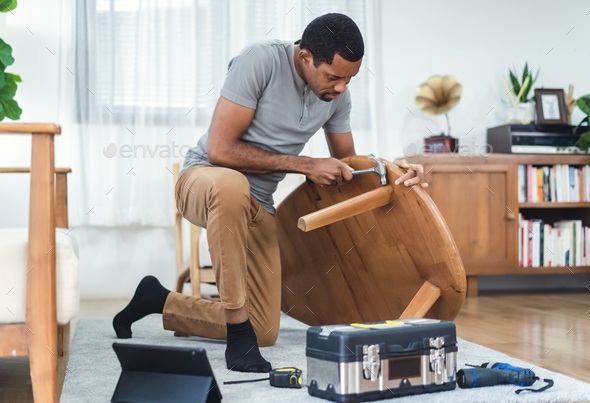 African American man watching online tutorial instructions for assembling furniture