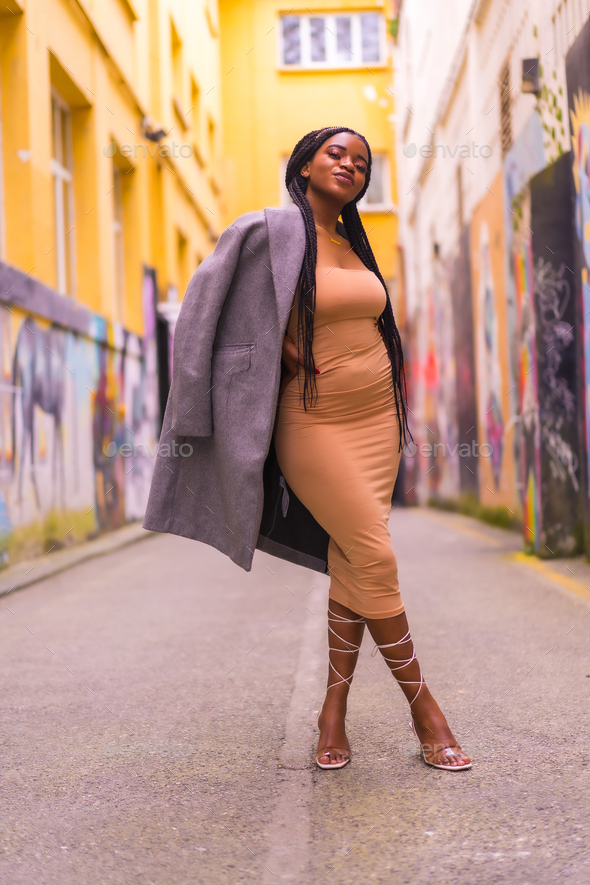 Trendy urban style with a black African girl in a cream colored dress on a  city street Stock Photo by Unai82