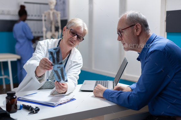 Woman doctor and man analyzing x ray scan exam results at checkup appointment
