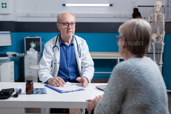 Physician attending consultation appointment with aged patient in ...