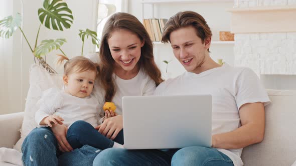Caucasian Family Young Parents and Little Daughter Child Girl Sitting on Couch at Home Buying Goods alt