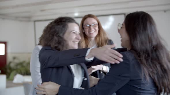Businesswomen Hugging and Triumphing in Office alt