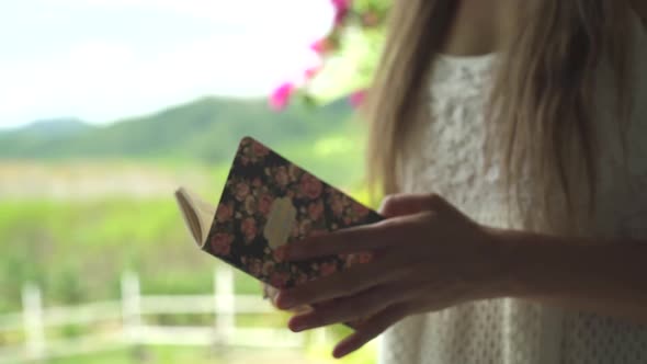 Wedding ceremony. Bride opens vintage notebook with vow. Green palm trees, pink flowers, marriage. alt