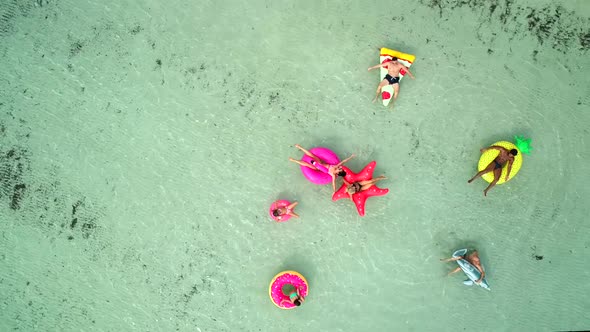 Aerial view of friends floating on inflatable mattresses in transparent sea. alt
