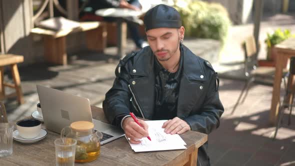 Inspired Concentrated Talented Gay Man Drawing Underwear Sketch Sitting in Outdoor Cafe on Sunny Day alt