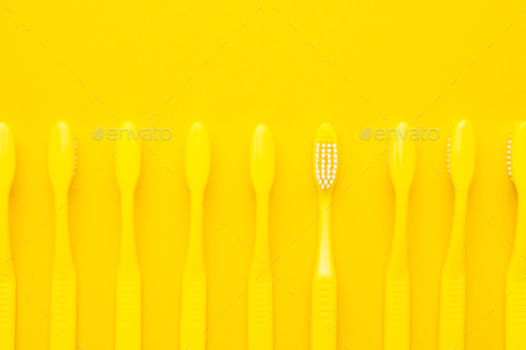 Minimalist Photo Of Yellow Toothbrushes Turned Down And One Of Them Turned Up