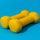 Photo of Yellow Fitness Dumbbells Over Blue Backgound - PhotoDune Item for Sale