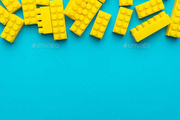 Yellow Plastic Building Blocks on Turquoise Blue Background with Copy Space - Stock Photo - Images