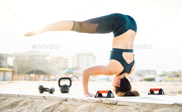 Athletic woman exercising calisthenic balance move at beach location