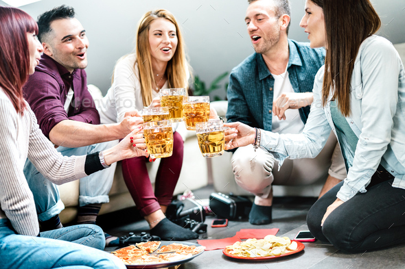 Young student friends toasting beer at home party after college time
