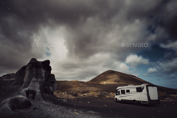 Modern camper van camp site in a scenic landscape destination with mountains and cloudy sky
