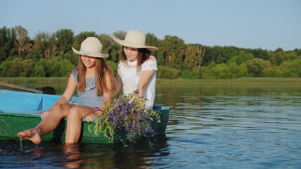 Mom with Daughter in Hats Sail in a Wooden Boat alt