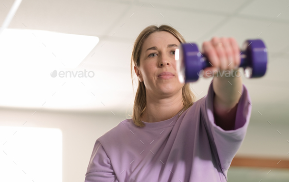 waist up portrait of real woman working out with dumbbells at gym, alone training, workout routine.