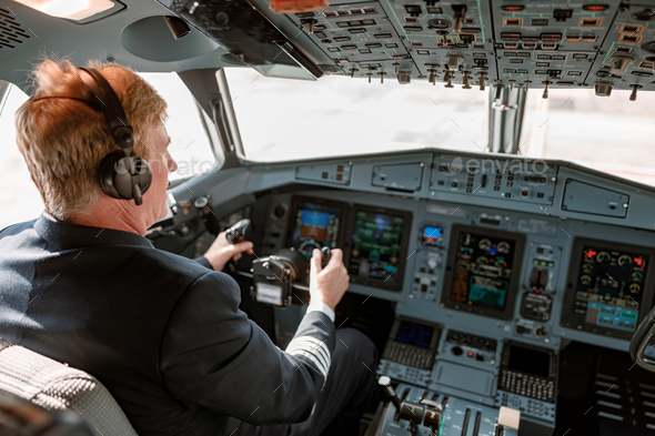 Male pilot controlling airplane flight from cockpit