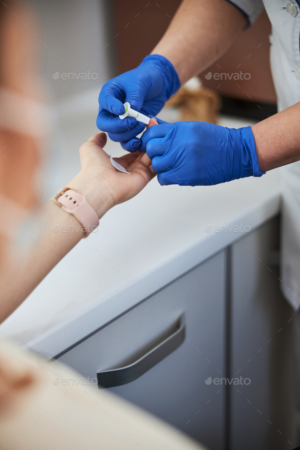 Nurse carrying out a finger prick test using a lancet Stock Photo by svitlanah
