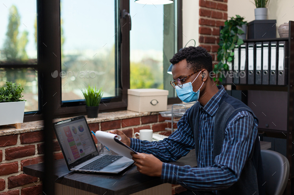 Portrait of marketing specialist with glasses wearing face mask and wireless earbuds focused on