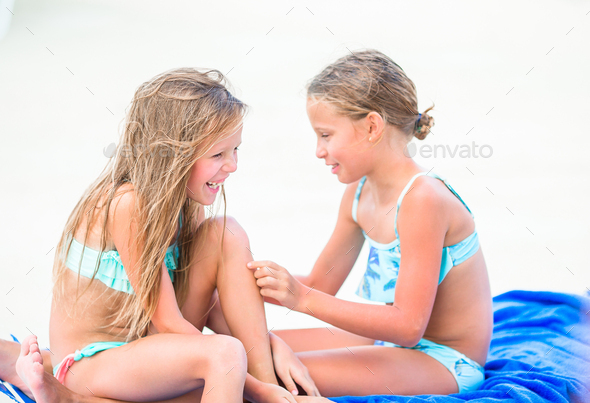 Two little happy girls have a lot of fun at tropical beach playing together  Stock Photo by travnikovstudio