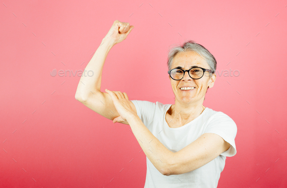Old woman grabbing her arm muscle with strong attitude, woman power and feminism