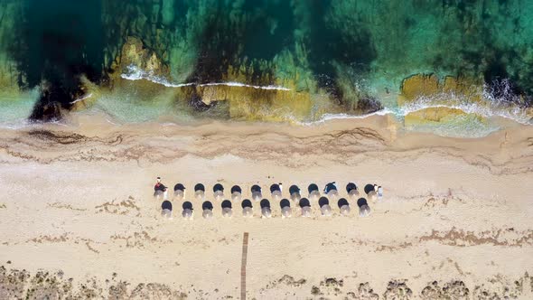 Umbrellas lined up on the sandy beach by the turquoise sea. alt