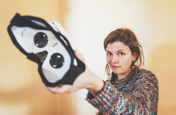Forced perspective image of a young woman holding the lenses of a vr glasses of cardboard