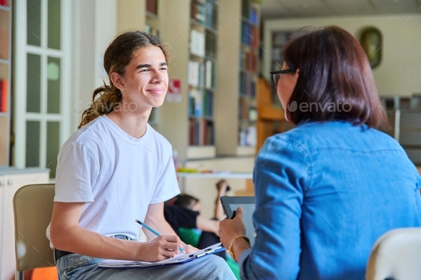 Woman school psychologist teacher talking and helping student, male teenager