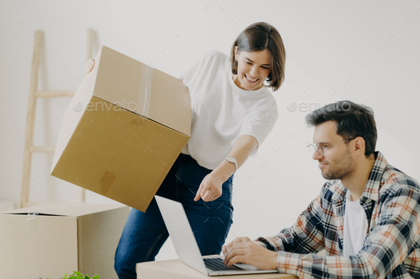 Happy family couple look attentively at laptop computer, search good moving company