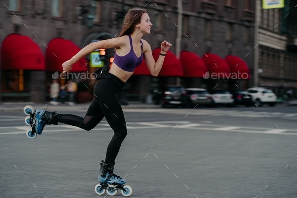 Active slim young woman rides fast on rollerskates improves balance agility and coordination