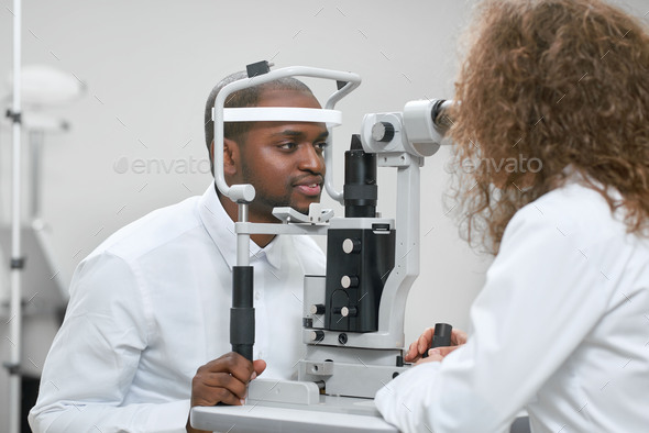Sideview of patient looking at apparatus during vision checking with oculist