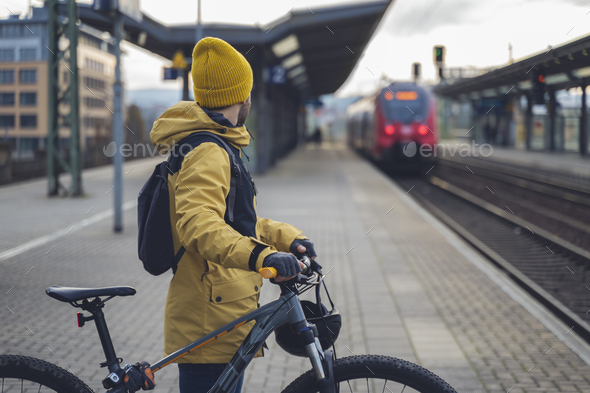 A man waiting with his bike the train.