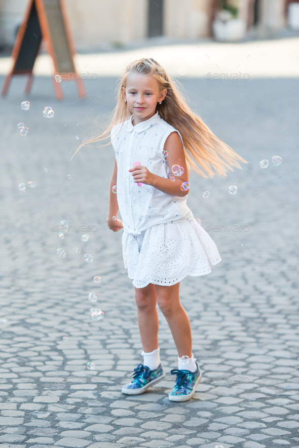 Adorable little girl blowing soap bubbles in Trastevere in Rome, Italy