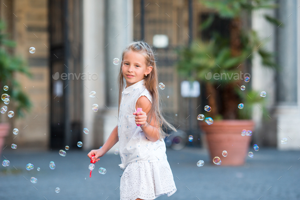 Adorable little girl blowing soap bubbles in Trastevere in Rome, Italy