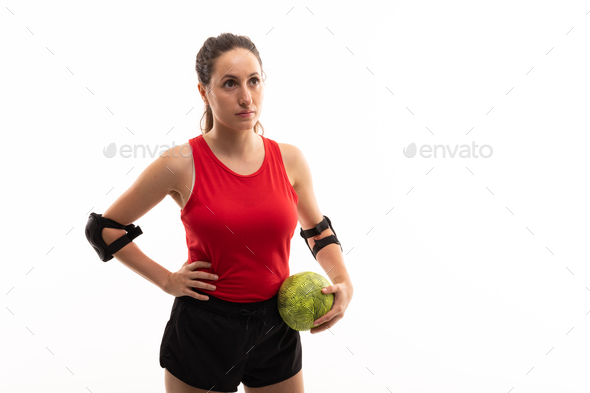 Caucasian young female handball player looking away while standing with ball and hand on hip