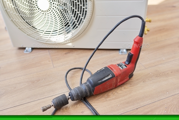 Repair, installation, background outdoor unit of air conditioner drill indoors on the floor