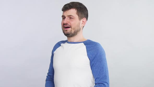 Sick Bearded Man Sneezing Into His White Tissue Isolated on Grey Background alt