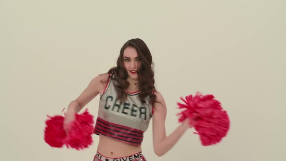 A Girl Dancing a Jubilant Dance with Pompoms in the Studio on a White Background alt