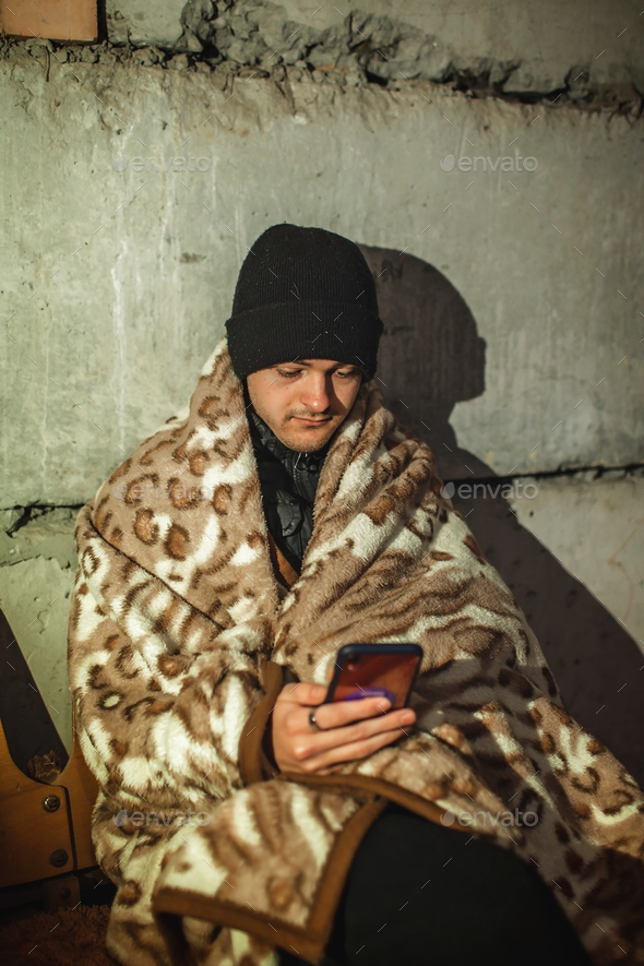 Ukrainian young man sits in bomb shelter and reads latest breaking news about the war
