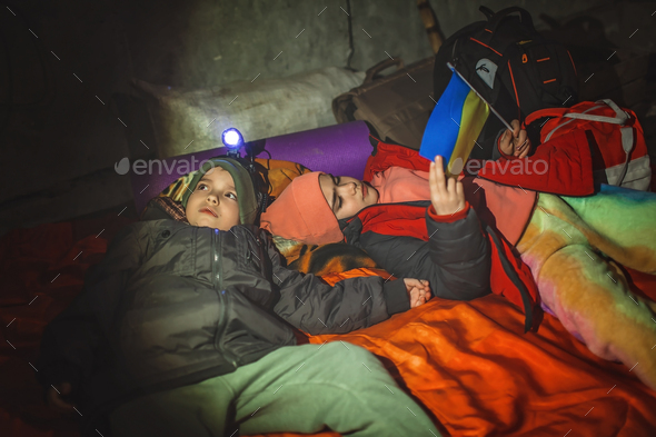 Kids with Ukrainian flag lay in bomb shelter and waits for end of airstrikes