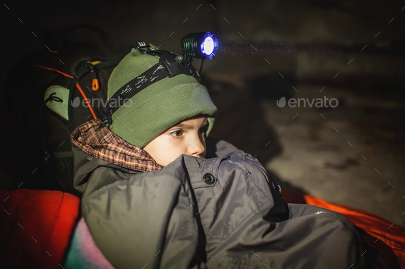 Ukrainian boy with headlamp lay in bomb shelter and waits for end of airstrikes