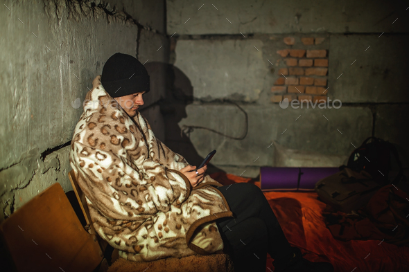Ukrainian young man sits in bomb shelter and reads latest braking news about the war